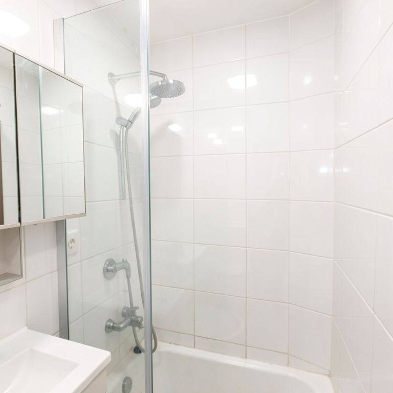 a small bathroom with a glass shower enclosure, a mirrored cabinet, and a glossy white tile wall, making the room feel spacious and bright, no text, no words, no letters, no signs, no watermarks a small bathroom with a glass shower enclosure, a mirrored cabinet, and a glossy white tile wall, making the room feel spacious and bright, no text, no words, no letters, no signs, no watermarks